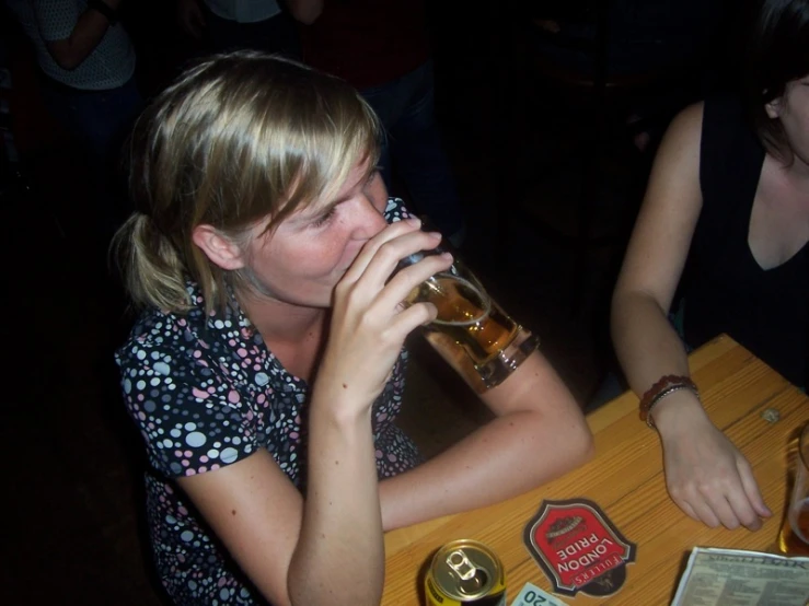 two women sitting at a table with drinks in hand