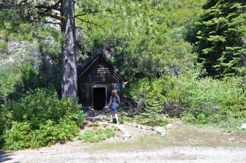 a woman standing outside of a wooden house