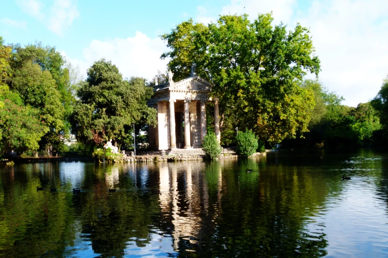 an old pavilion is reflecting the landscape and trees