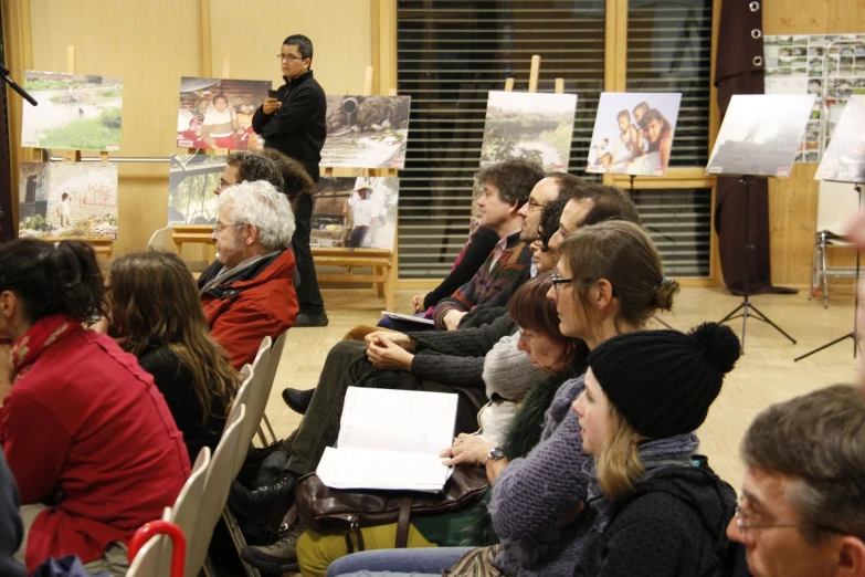 people in chairs with laptops and various art pieces