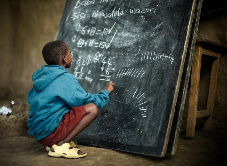 a young man writes on a chalkboard in the dark