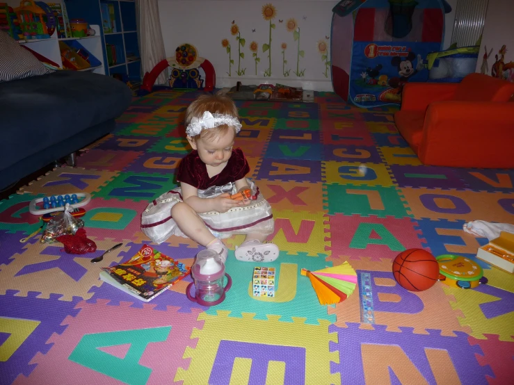 a little girl on the floor sitting with toys