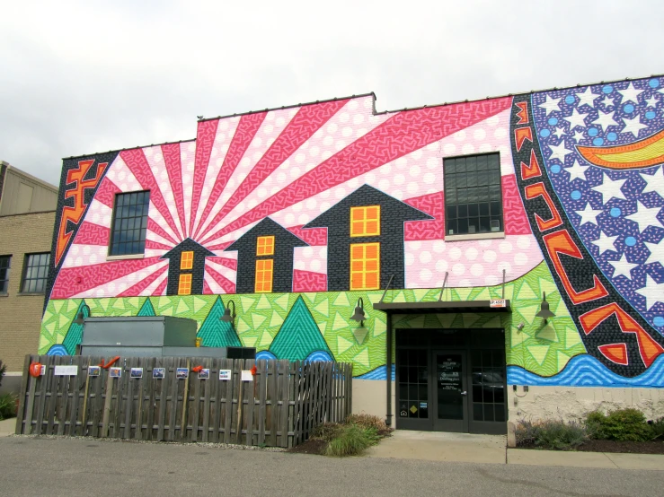 a large painting of a colorful house on the side of a building