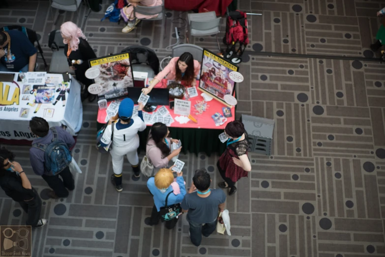 an overhead view shows several people sitting at a booth and standing around