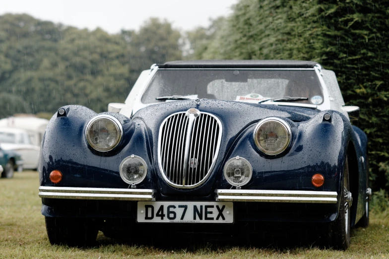 old fashion car parked in a field near parked trucks