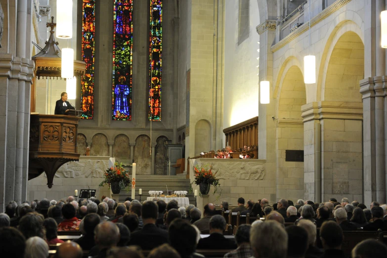 a church with people sitting down in the pews and one man is speaking