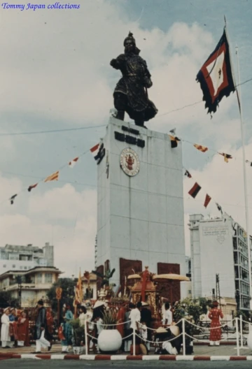 an indian statue on top of a building with flags in the background