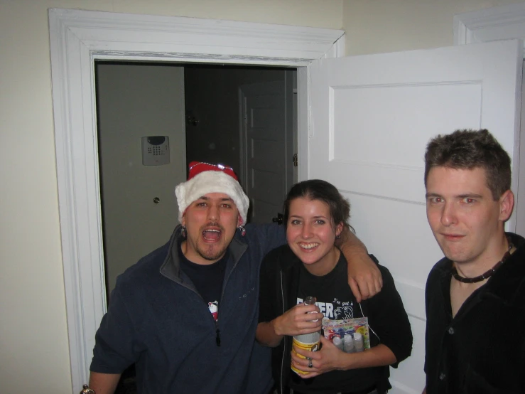 three people stand together in a bathroom holding cans