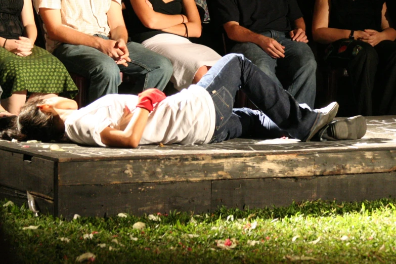 a young person laying on top of a wooden box next to some people
