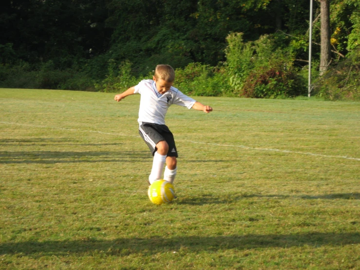 a boy wearing a uniform playing soccer on the field