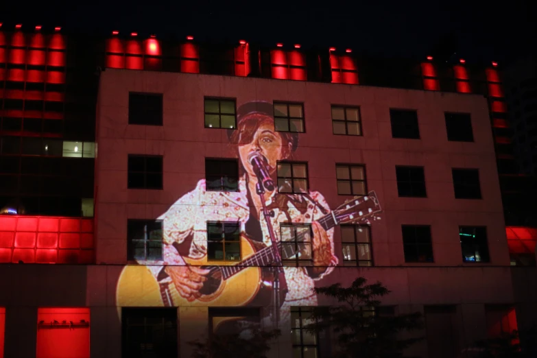 a building with a projected image of a man playing a guitar in front of it