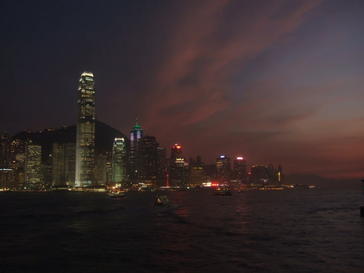 the city at night with tall buildings on the shoreline