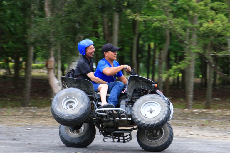 two men sitting on a four - wheeler on a trail