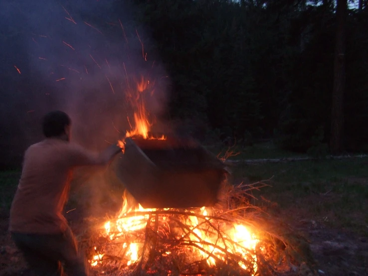 a young man standing next to a fire pit