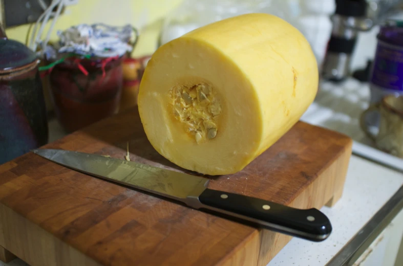 a knife is sitting on a wooden  board near a peeled melon