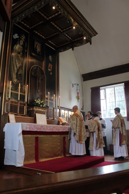 people are standing around a church alter with the priest looking on