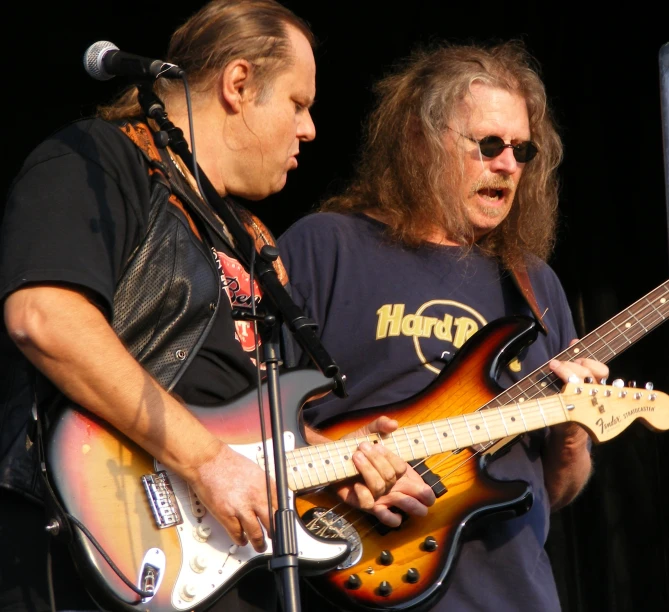 two men are playing guitars and one has an orange guitar