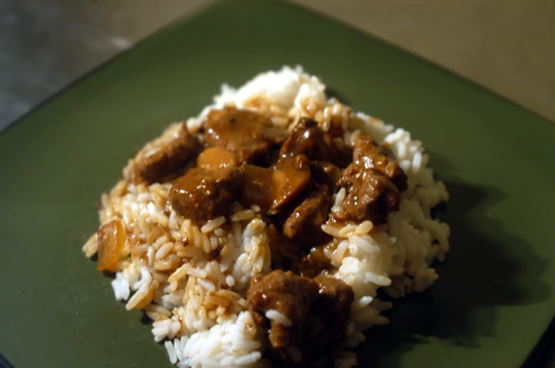 a plate with rice, meat and sauce on top