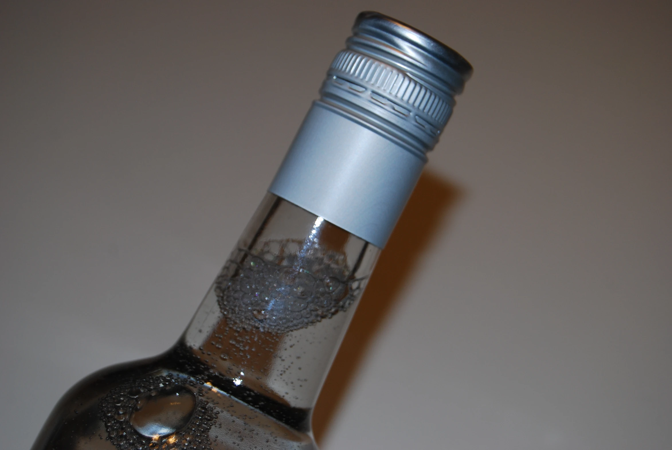 an empty glass bottle filled with water sits on a table