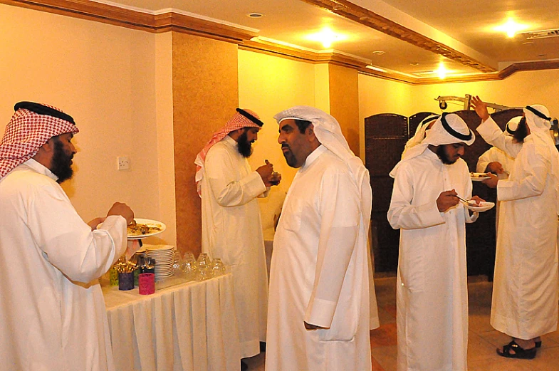 men dressed in white eating at tables in a room