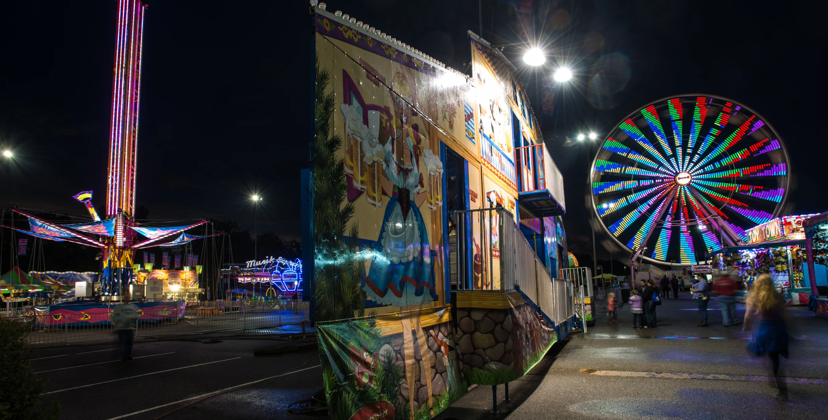 a colorful carnival with ferris wheel lit up in the background