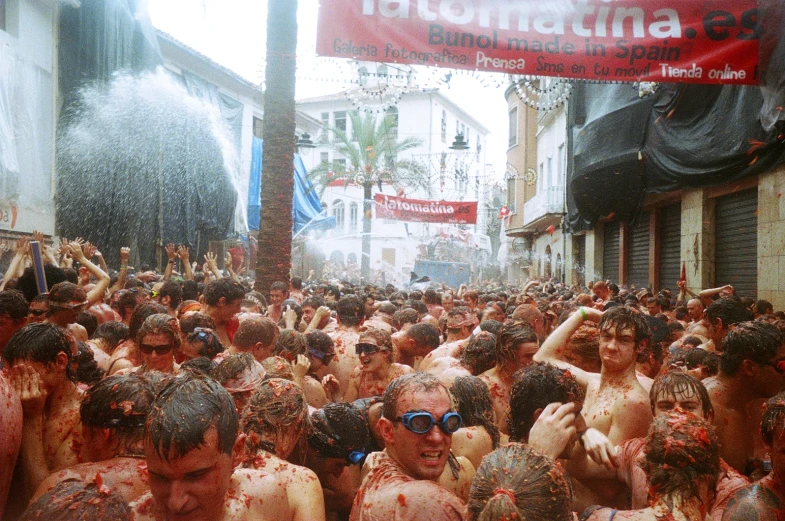 many people gathered in the street in white and brown paint and a red sign