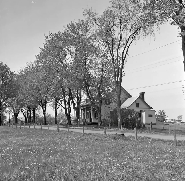 black and white po of an old house with trees in the yard