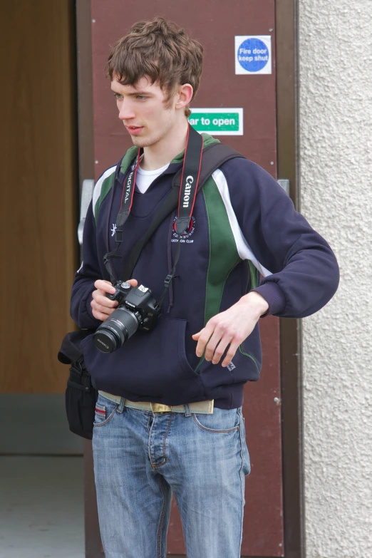 a young man standing in front of a building with a camera