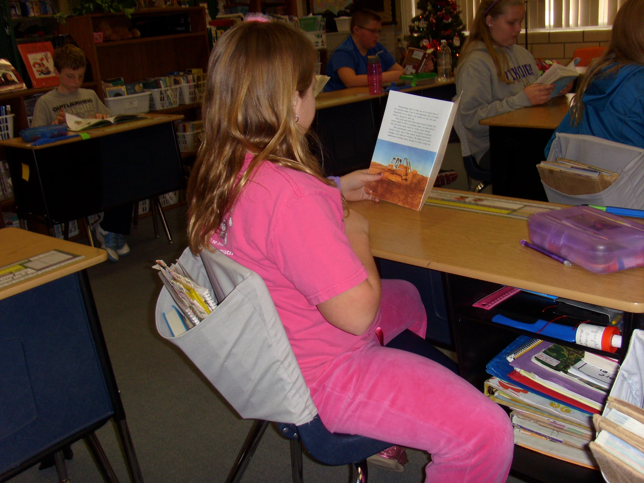 little girl sitting at table reading to adult