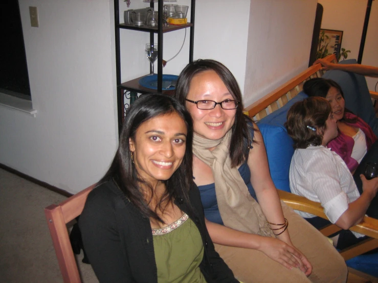 two women sitting next to each other with other people behind them