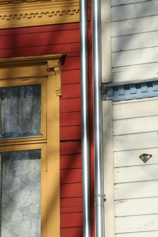 two windows in different colors are seen on a red house