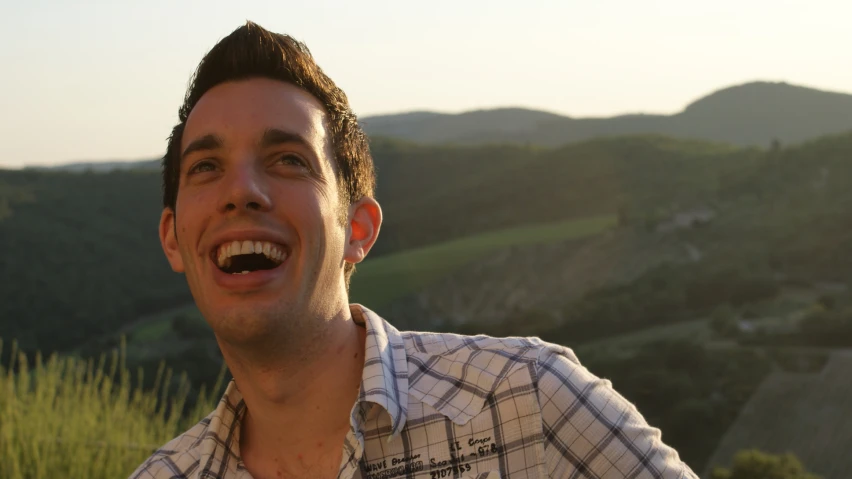 a man smiling in front of mountains