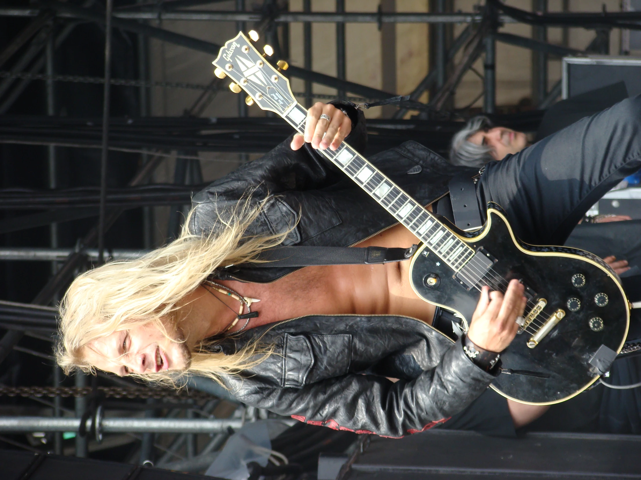 a man in jeans holding his guitar by another person