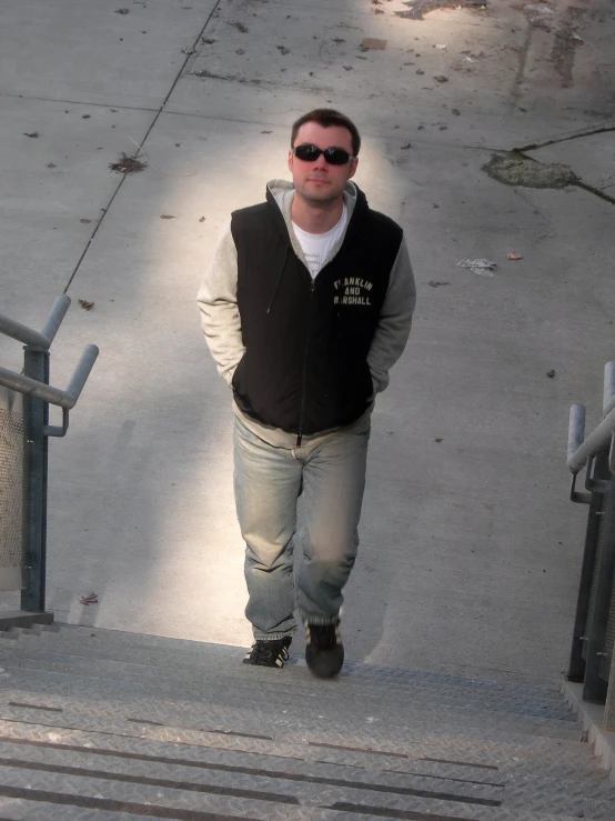 a man wearing a vest is standing on the concrete