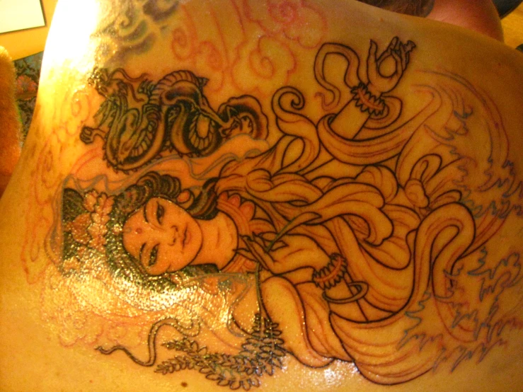 a tattoo featuring a woman with long hair and fish
