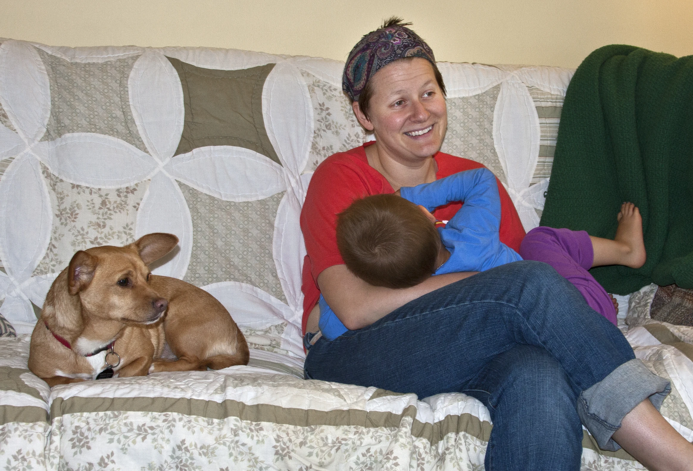 woman sitting on couch with baby in lap next to dog