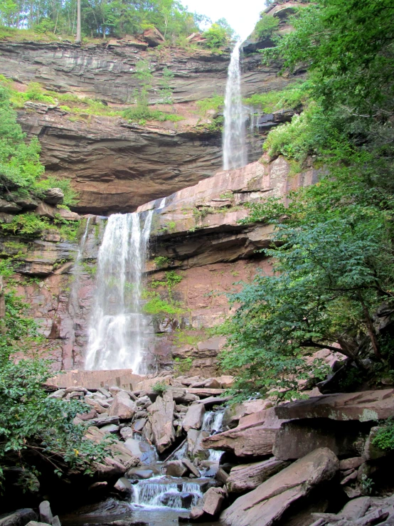 large waterfall near rocky cliff with small stream in foreground