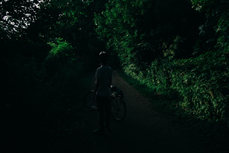 a man on the side of a trail holding his bike