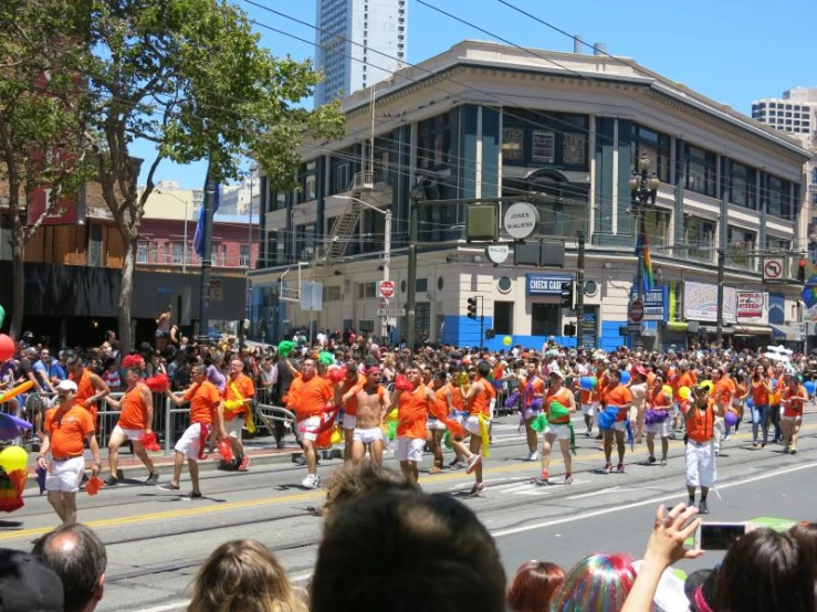 many people in orange and blue shirts and some buildings