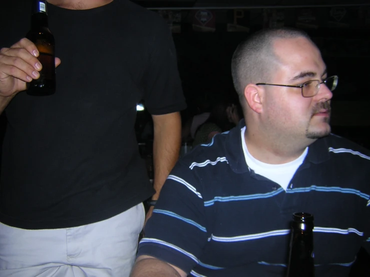 two men at a bar with beers in hand