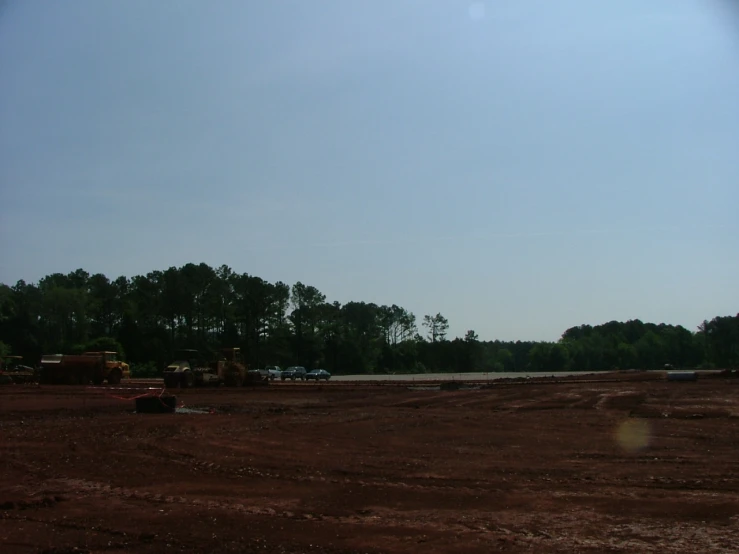 large area with dirt, trees, trucks and other animals