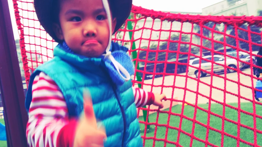 small child wearing hat and vest holding a marker