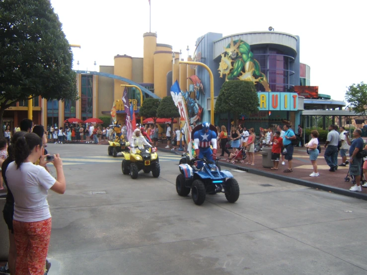 three people on four wheelers driving down a street