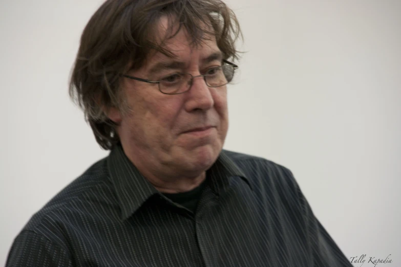 a man looking straight ahead wearing glasses and a black shirt