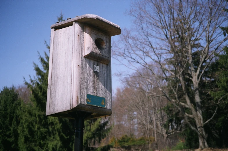 an old bird house sitting on top of a pole in a grassy field