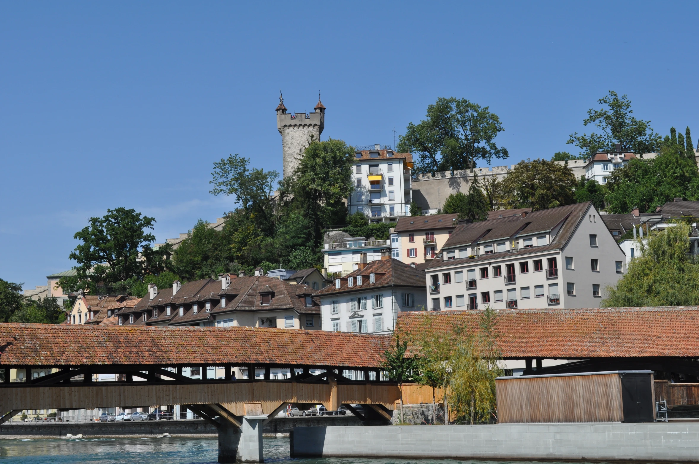 an old bridge crosses the river in front of some older buildings