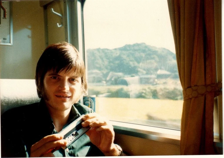 a man holding a camera and looking out the window