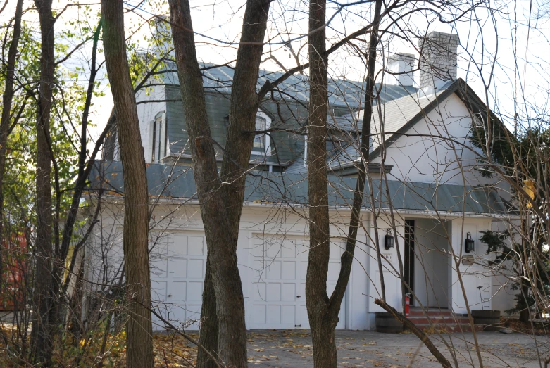 a white house in a wooded area with white garage