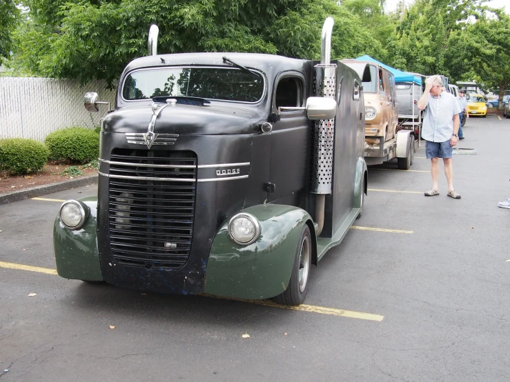 two men standing in the parking lot with an old, classic looking truck