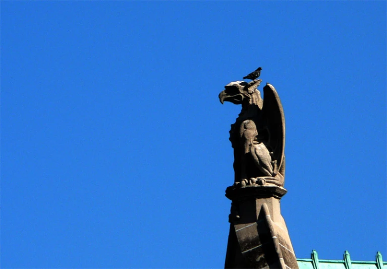 a statue on top of a building with a bird sitting on it